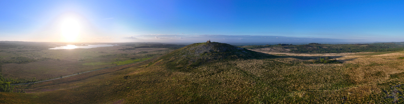 Aerial view of Chapelle Saint Michel de Brasparts on a rocky hilltop overlooking the vast moorland and a distant lake under a bright sun Saint Rivoal Bretagne France. Aerial view of Chapelle Saint Michel de Brasparts on a rocky hilltop overlooking the vast moorland and a distant lake under a bright sun Saint Rivoal Bretagne France.