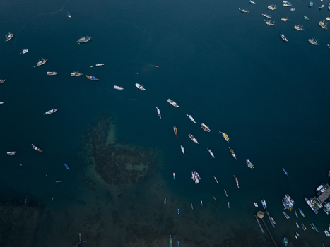 Aerial view of Labuan Bajo harbor with numerous boats anchored in the deep blue sea off the coast of Komodo East Nusa Tenggara Indonesia. Aerial view of Labuan Bajo harbor with numerous boats anchored in the deep blue sea off the coast of Komodo East Nusa Tenggara Indonesia.