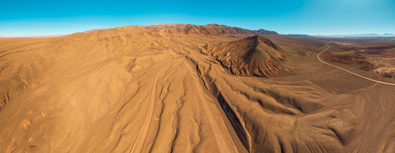 Aerial view of the vast arid landscape of the Atacama Desert with winding dirt roads and rugged mountain formations in San Pedro de Atacama Antofagasta Chile. Aerial view of the vast arid landscape of the Atacama Desert with winding dirt roads and rugged mountain formations in San Pedro de Atacama Antofagasta Chile.