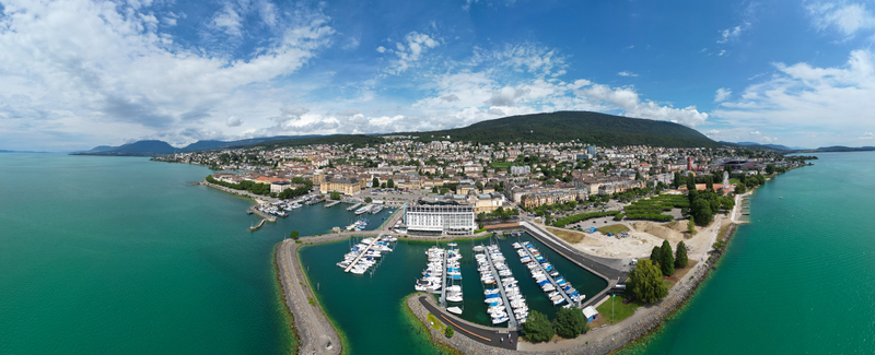 Aerial view of the vibrant cityscape meets the turquoise waters of Lake Neuchâtel with a bustling marina and distant mountains Neuchâtel Neuchâtel Switzerland. Aerial view of the vibrant cityscape meets the turquoise waters of Lake Neuchâtel with a bustling marina and distant mountains Neuchâtel Neuchâtel Switzerland.
