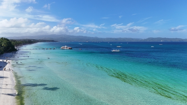 Malay Philippines 01 May 2026 Aerial view of Boracay Island featuring the turquoise waters of White Beach with people walking on the sand and boats anchored offshore under a blue sky. Malay Philippines 01 May 2026 Aerial view of Boracay Island featuring the turquoise waters of White Beach with people walking on the sand and boats anchored offshore under a blue sky.