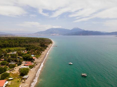 Aerial view of Karaot Beach with its sandy coastline lush green forests turquoise sea and distant mountains under a cloudy sky in Fethiye Mugla Turkiye. Aerial view of Karaot Beach with its sandy coastline lush green forests turquoise sea and distant mountains under a cloudy sky in Fethiye Mugla Turkiye.