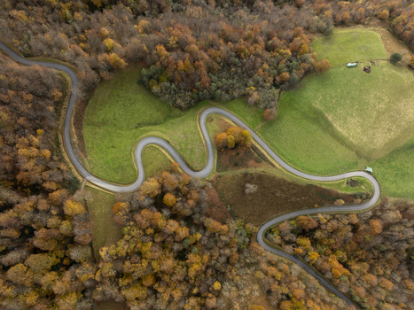 Aerial view of a winding road cutting through the colorful autumn forest and green pastures in the Pyrenees Spain. Aerial view of a winding road cutting through the colorful autumn forest and green pastures in the Pyrenees Spain.