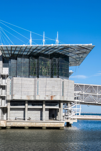 Lisboa Portugal 17 September 2026 View of Oceanario de Lisboa featuring modern glass and concrete architecture a suspended roof and waterfront setting under a clear blue sky. Lisboa Portugal 17 September 2026 View of Oceanario de Lisboa featuring modern glass and concrete architecture a suspended roof and waterfront setting under a clear blue sky.