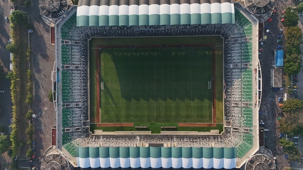 Aerial view of Maguwoharjo Stadium featuring a green football pitch and white and green seating in Kecamatan Depok Daerah Istimewa Yogya Indonesia.