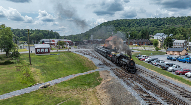 Aerial view of the historic East Broad Top Railroad steam train pulling into the station with smoke surrounded by rural landscape and historic buildings in Rockhill Pennsylvania United States. Aerial view of the historic East Broad Top Railroad steam train pulling into the station with smoke surrounded by rural landscape and historic buildings in Rockhill Pennsylvania United States.