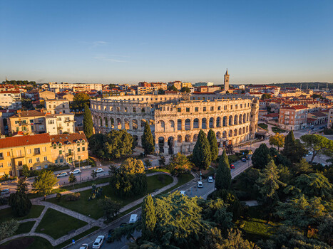 Aerial view of the ancient Roman amphitheater a majestic stone relic amidst a city bathed in the warm glow of the setting sun Pula Istria County Croatia.