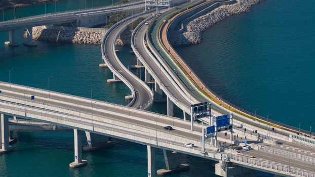 Aerial view of a modern highway interchange with curving bridges over the turquoise sea and rocky shoreline in Hong Kong Hong Kong.