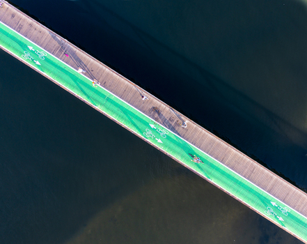 Aerial view of Tel Aviv Port featuring a wooden bridge with a vibrant green bicycle lane and cyclists riding over the water in Tel Aviv Yafo Tel Aviv District Israel. Aerial view of Tel Aviv Port featuring a wooden bridge with a vibrant green bicycle lane and cyclists riding over the water in Tel Aviv Yafo Tel Aviv District Israel.