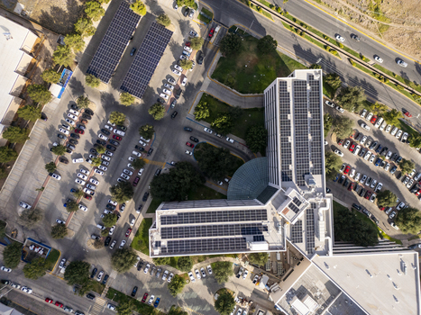 Aerial view of solar panels installed on the roof of a modern office building surrounded by parking lots and green spaces in Chihuahua Chihuahua Mexico. Aerial view of solar panels installed on the roof of a modern office building surrounded by parking lots and green spaces in Chihuahua Chihuahua Mexico.