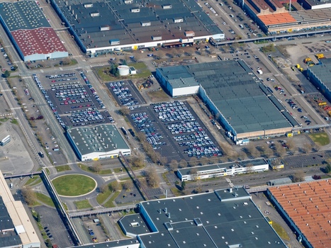 Aerial view of vast industrial buildings and extensive car parks create a geometric tapestry contrasting starkly with the roundabout s greenery Sausheim Grand Est France.