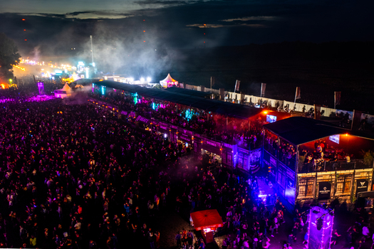 Herzogenaurach Germany 24 July 2025 Aerial view of Open Beatz Festival with a large crowd vibrant stage lighting and smoke effects at night.