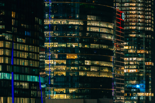 Warszawa Poland 07 September 2026 Aerial view of PZU SA tower illuminated at night with glowing office windows and modern glass facade in the city skyline.
