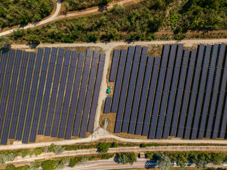 Aerial view of the Solarfeld solar farm with rows of photovoltaic panels arranged in a field surrounded by trees and dirt paths in Hombourg Grand Est France.