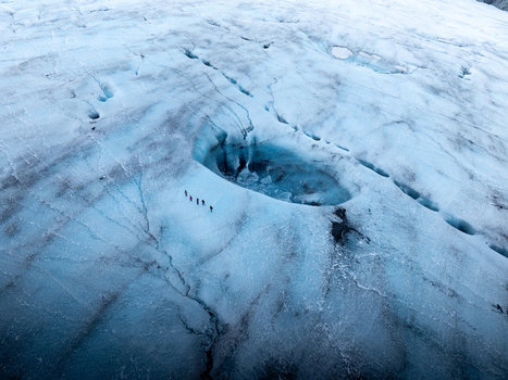 Aerial view of Breidamerkurjokull glacier with a group of people walking near a deep blue glacial meltwater pool in Sveitarfelagid Hornafjordur Iceland. Aerial view of Breidamerkurjokull glacier with a group of people walking near a deep blue glacial meltwater pool in Sveitarfelagid Hornafjordur Iceland.