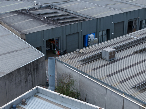 Melbourne VIC Australia 25 September 2026 Aerial view of industrial factory buildings with metal roofs ventilation units and storage containers.