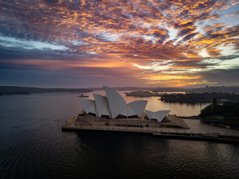 Aerial view of the iconic Sydney Opera House glows as a beacon beneath a sky ablaze with fiery hues and soft pastel shades Sydney New South Wales Australia. Aerial view of the iconic Sydney Opera House glows as a beacon beneath a sky ablaze with fiery hues and soft pastel shades Sydney New South Wales Australia.