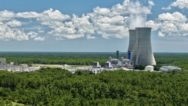 Aerial view of the Seminole Electric Cooperative power plant with cooling towers industrial infrastructure and surrounding forest under a blue sky in Palatka Florida United States.