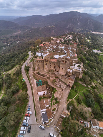 Aerial view of the ancient Castellar Viejo castle perched atop a hill surrounded by rolling hills and lush greenery Castellar de la Frontera Andalucía Spain. Aerial view of the ancient Castellar Viejo castle perched atop a hill surrounded by rolling hills and lush greenery Castellar de la Frontera Andalucía Spain.