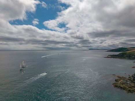 Aerial view of sailboats and motorboats navigating the Fowey River along the rugged coastline of Fowey Cornwall United Kingdom. Aerial view of sailboats and motorboats navigating the Fowey River along the rugged coastline of Fowey Cornwall United Kingdom.