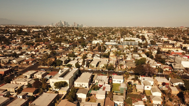 Aerial view of the Los Angeles skyline rising above the residential neighborhoods and palm trees under a clear sky in Los Angeles California United States. Aerial view of the Los Angeles skyline rising above the residential neighborhoods and palm trees under a clear sky in Los Angeles California United States.