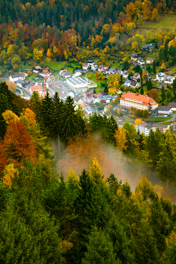 View of a village nestled in the Black Forest with vibrant autumn foliage and morning mist in Offenburg Baden Wurttemberg Germany. View of a village nestled in the Black Forest with vibrant autumn foliage and morning mist in Offenburg Baden Wurttemberg Germany.