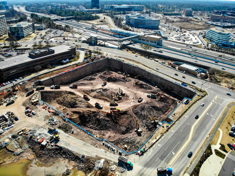 Reston Virginia United States 12 March 2019 Aerial view of a large construction site excavation with heavy machinery and dump trucks surrounded by buildings. Reston Virginia United States 12 March 2019 Aerial view of a large construction site excavation with heavy machinery and dump trucks surrounded by buildings.
