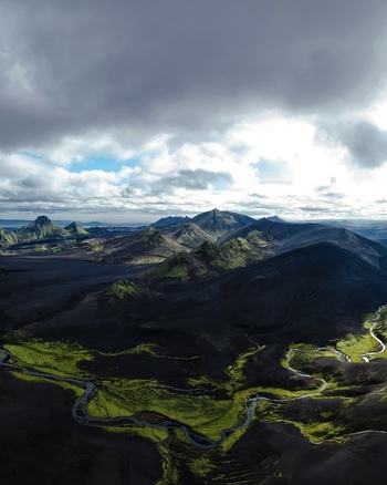 Aerial view of the dramatic contrast between the dark volcanic land and vibrant green vegetation winding river carving through the landscape Iceland. Aerial view of the dramatic contrast between the dark volcanic land and vibrant green vegetation winding river carving through the landscape Iceland.