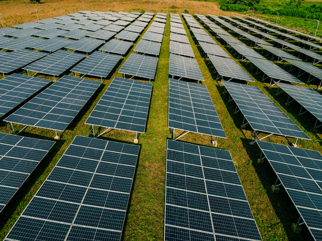 Aerial view of a large solar panel farm with rows of photovoltaic panels installed on a grassy field in Ogun State Nigeria.