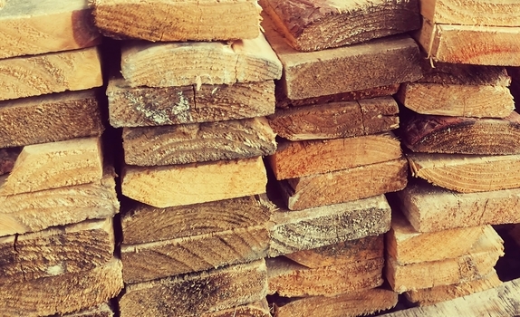 View of stacked wooden planks and timber poles in a lumber yard in Pretoria Gauteng South Africa.