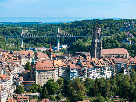 Aerial view of St Nicolas Cathedral and the historic old town with red rooftops and the modern Poya Bridge spanning the valley in Fribourg Fribourg Switzerland. Aerial view of St Nicolas Cathedral and the historic old town with red rooftops and the modern Poya Bridge spanning the valley in Fribourg Fribourg Switzerland.
