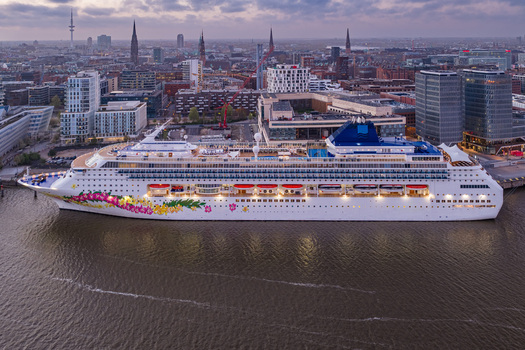 Aerial view of the Cruise Center HafenCity with a large cruise ship docked at the terminal against the city skyline at twilight in Hamburg Hamburg Germany.