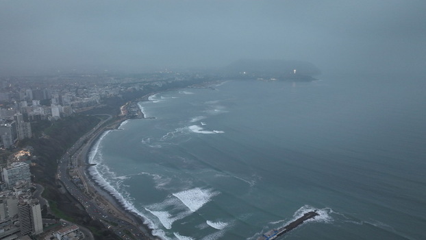 Aerial view of the coastline of Miraflores with Pacific Ocean waves coastal highway and city buildings under a cloudy sky in Miraflores Provincia de Lima Peru. Aerial view of the coastline of Miraflores with Pacific Ocean waves coastal highway and city buildings under a cloudy sky in Miraflores Provincia de Lima Peru.