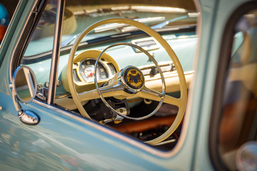 View of a vintage car s interior with a cream steering wheel against the car s light blue exterior evoking a sense of nostalgia Pula Istria County Croatia.