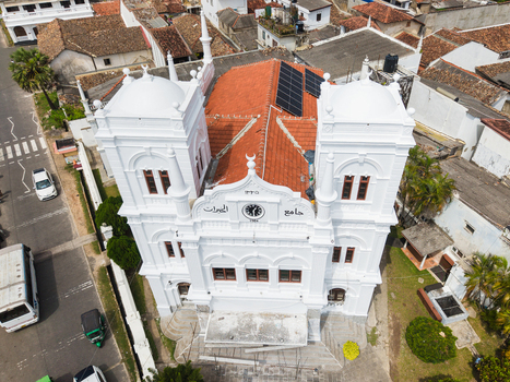 Aerial view of the white Meeran Jumma Mosque featuring two towers and solar panels on a red tiled roof in the historic fort area Galle Southern Province Sri Lanka. Aerial view of the white Meeran Jumma Mosque featuring two towers and solar panels on a red tiled roof in the historic fort area Galle Southern Province Sri Lanka.