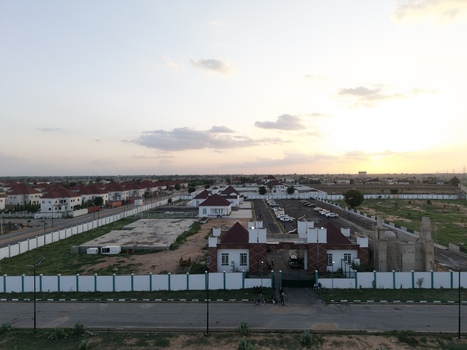 Aerial view of a modern residential complex with white houses and red roofs under a soft sunset sky in Kano Kano Nigeria.