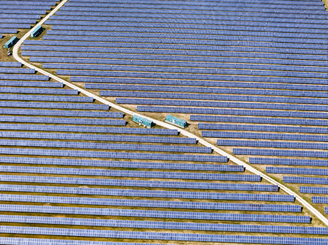 Aerial view of a vast solar farm with rows of blue photovoltaic panels and a service road under bright sunlight in Torrazza Piemonte Piemonte Italy. Aerial view of a vast solar farm with rows of blue photovoltaic panels and a service road under bright sunlight in Torrazza Piemonte Piemonte Italy.