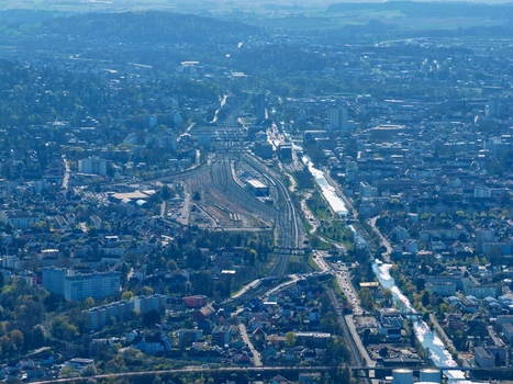Aerial view of the intricate railway lines cutting through the city juxtaposed against the winding river and dense urban landscape Sausheim Grand Est France.