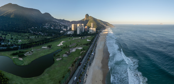 Aerial view of Sao Conrado beach and golf course with high rise buildings nestled against lush mountains along the Atlantic coastline in Rio de Janeiro State of Rio de Janeiro Brazil.