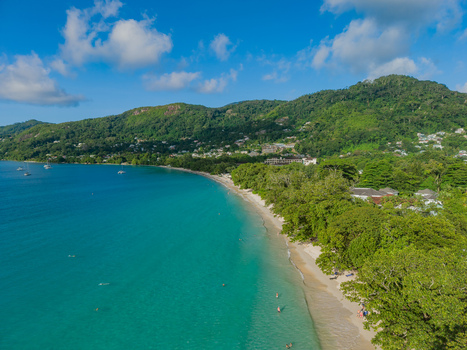 Aerial view of turquoise waters meet lush green forests along the sandy shore a vibrant contrast under the scattered clouds Victoria Seychelles. Aerial view of turquoise waters meet lush green forests along the sandy shore a vibrant contrast under the scattered clouds Victoria Seychelles.