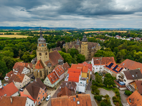 Aerial view of Neuenstein Castle surrounded by historic town rooftops a church tower and lush green landscape in Neuenstein Baden Wurttemberg Germany. Aerial view of Neuenstein Castle surrounded by historic town rooftops a church tower and lush green landscape in Neuenstein Baden Wurttemberg Germany.