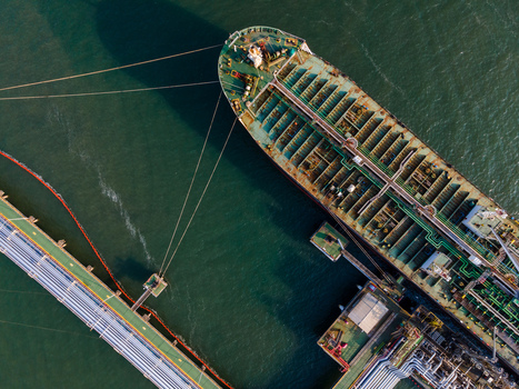 Aerial view of a large tanker ship moored at an industrial terminal with pipelines and mooring lines visible in the water in Cilacap Regency Central Java Indonesia. Aerial view of a large tanker ship moored at an industrial terminal with pipelines and mooring lines visible in the water in Cilacap Regency Central Java Indonesia.