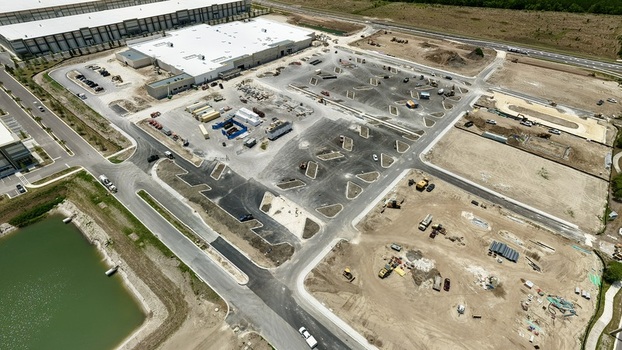 Aerial view of the construction site at Foundry Lane featuring industrial warehouses heavy machinery and a retention pond in World Golf Village Florida United States.