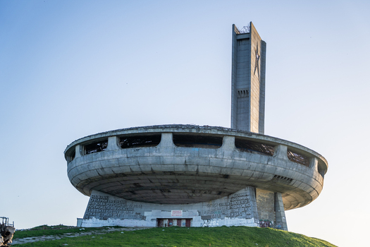 View of the abandoned Buzludzha Monument with its iconic saucer shaped concrete structure and tall tower set against a clear blue sky in Stara Zagora Bulgaria. View of the abandoned Buzludzha Monument with its iconic saucer shaped concrete structure and tall tower set against a clear blue sky in Stara Zagora Bulgaria.