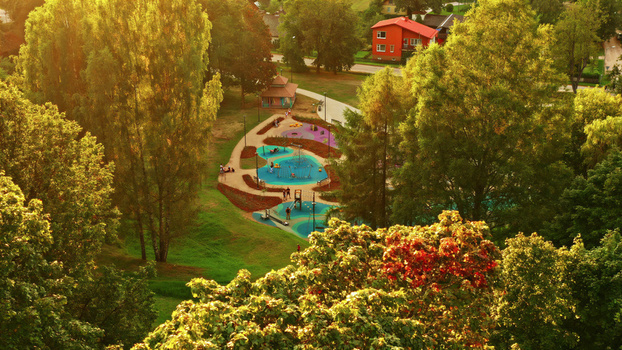 Aerial view of a colorful playground nestled among lush green trees in a park during golden hour in Latvija. Aerial view of a colorful playground nestled among lush green trees in a park during golden hour in Latvija.