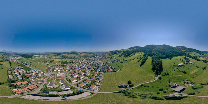 Aerial view of the town of Root featuring residential houses green meadows and rolling hills under a clear blue sky in Root Lucerne Switzerland. Aerial view of the town of Root featuring residential houses green meadows and rolling hills under a clear blue sky in Root Lucerne Switzerland.