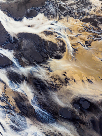 Aerial view of intricate braided glacial river patterns flowing through dark volcanic sand in Iceland. Aerial view of intricate braided glacial river patterns flowing through dark volcanic sand in Iceland.