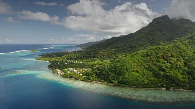 Aerial view of the lush green coastline and turquoise lagoon of Moorea with coral reefs and tropical vegetation in Moorea Maiao Windward Islands French Polynesia. Aerial view of the lush green coastline and turquoise lagoon of Moorea with coral reefs and tropical vegetation in Moorea Maiao Windward Islands French Polynesia.