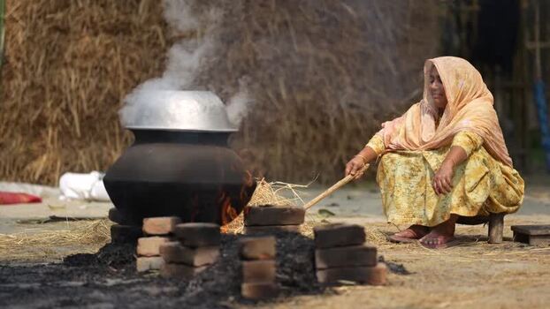 View of a woman cooking over an open fire in Bogura Bangladesh.