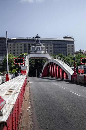 View of the historic Swing Bridge with its distinctive red metal structure and control tower set against the backdrop of the Hilton hotel in Newcastle upon Tyne England United Kingdom. View of the historic Swing Bridge with its distinctive red metal structure and control tower set against the backdrop of the Hilton hotel in Newcastle upon Tyne England United Kingdom.